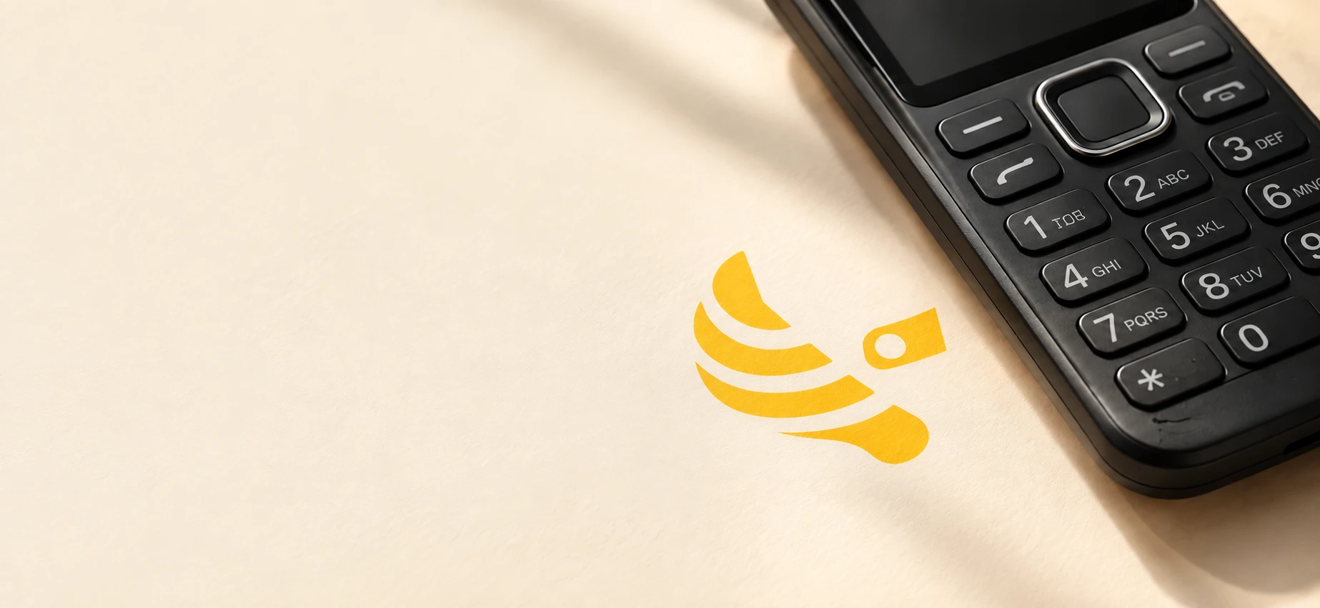 Close-up of a feature phone beside the yellow ZebraWallet emblem